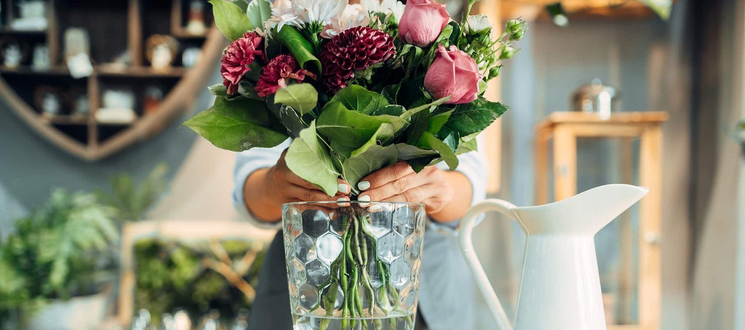 female florist puts flower bouquet into a vase 2021 08 26 16 26 51 utc 1 scaled